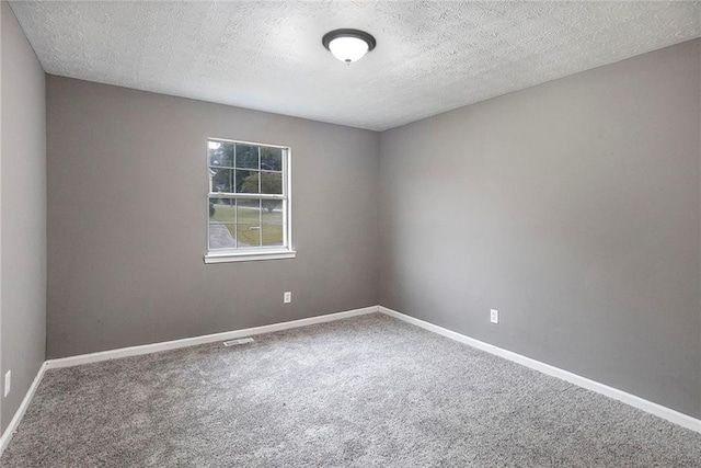 empty room with a textured ceiling, carpet, and baseboards