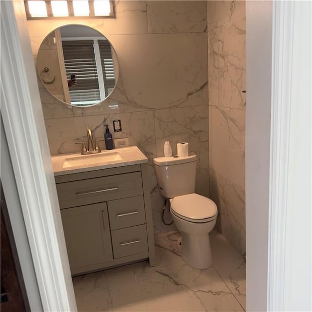 bathroom featuring decorative backsplash, tile walls, vanity, and toilet