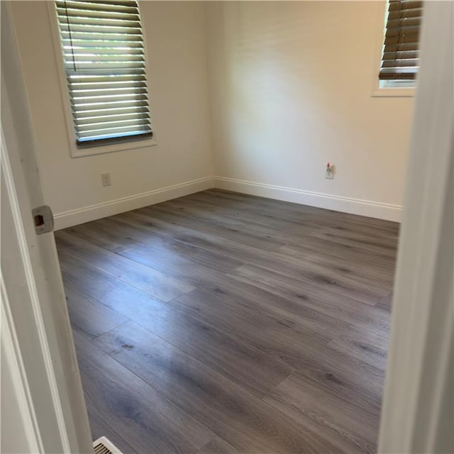 unfurnished room with dark wood-type flooring