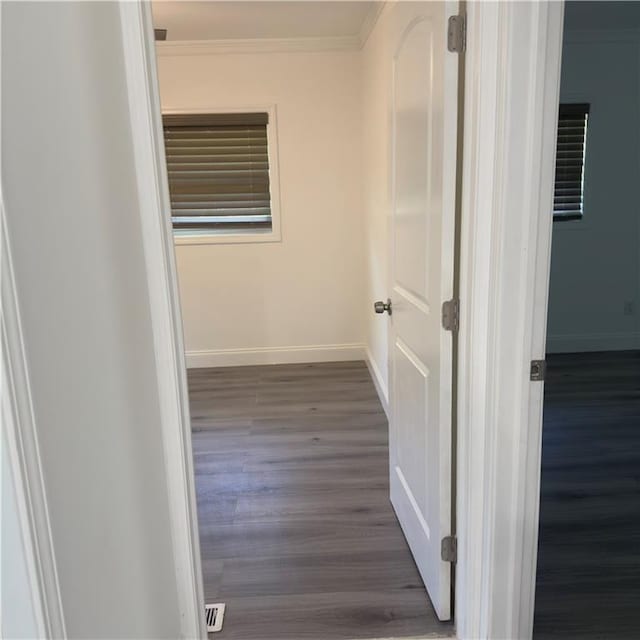 corridor with ornamental molding and dark wood-type flooring