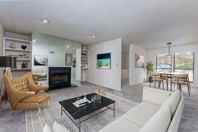 living area with light carpet, a fireplace with raised hearth, and a textured ceiling