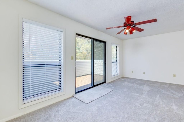 carpeted empty room with a ceiling fan and a textured ceiling