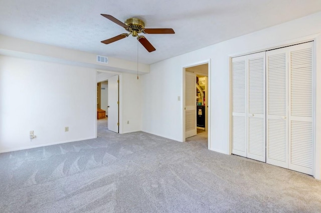 unfurnished bedroom with carpet flooring, a ceiling fan, visible vents, and a closet