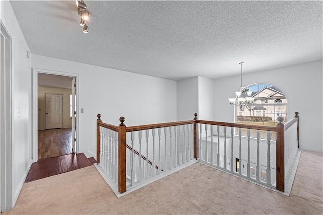 hall with an upstairs landing, a notable chandelier, a textured ceiling, and carpet floors