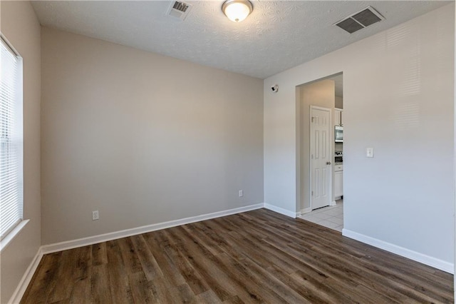 spare room with a textured ceiling and hardwood / wood-style flooring