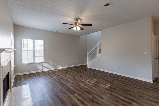 unfurnished living room featuring ceiling fan, dark hardwood / wood-style floors, and a textured ceiling