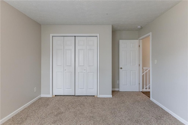 unfurnished bedroom featuring a textured ceiling, a closet, and carpet