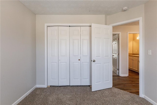 unfurnished bedroom with dark carpet, a closet, and a textured ceiling