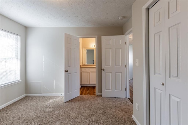 unfurnished bedroom featuring a textured ceiling, a closet, carpet floors, and multiple windows