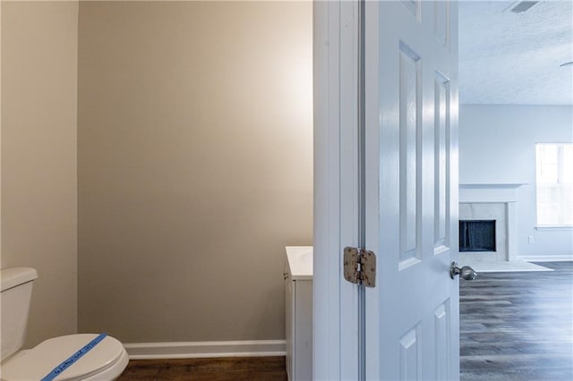 bathroom featuring toilet, a textured ceiling, wood-type flooring, and vanity