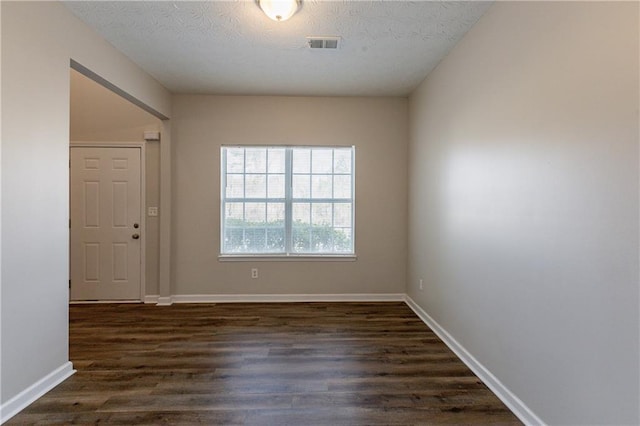 spare room featuring a textured ceiling and dark hardwood / wood-style flooring