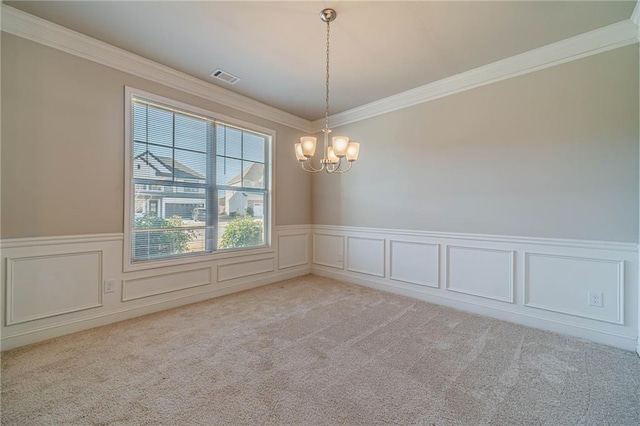 empty room featuring visible vents, a wainscoted wall, carpet floors, crown molding, and a chandelier