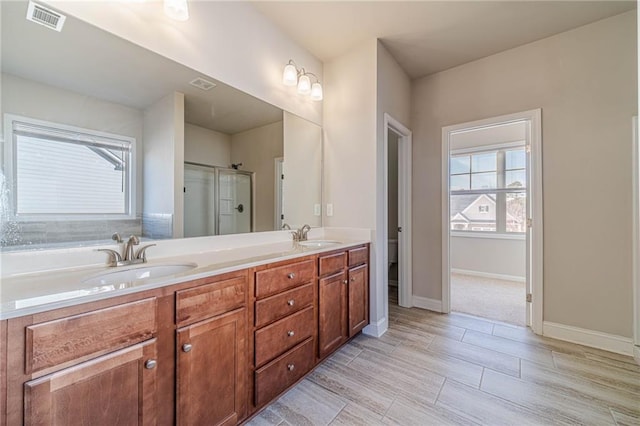 full bath with a sink, visible vents, a stall shower, and double vanity