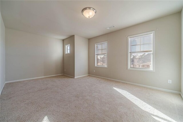 spare room featuring carpet flooring, visible vents, and baseboards