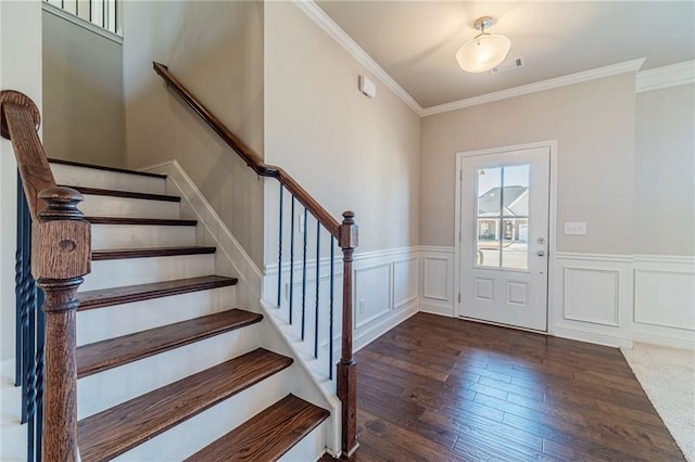 entryway featuring visible vents, wood finished floors, a decorative wall, wainscoting, and crown molding