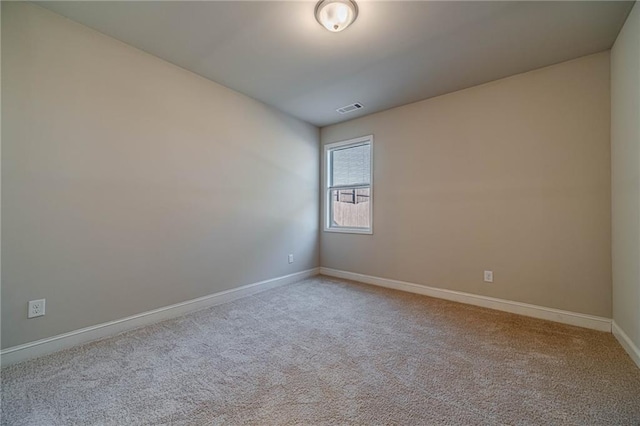 empty room featuring light carpet, visible vents, and baseboards