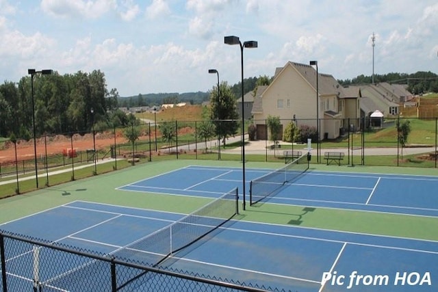 view of tennis court with community basketball court and fence