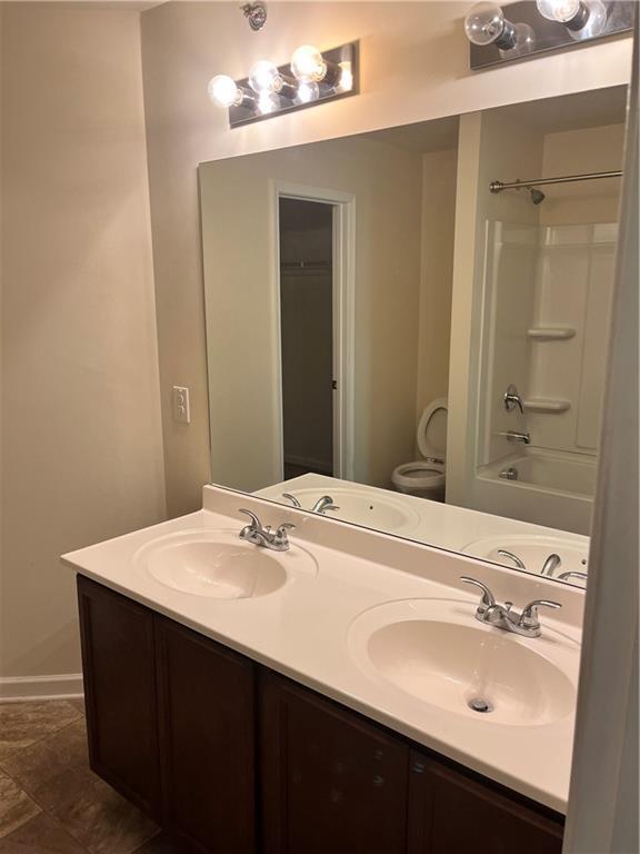 full bath featuring toilet, double vanity, and a sink