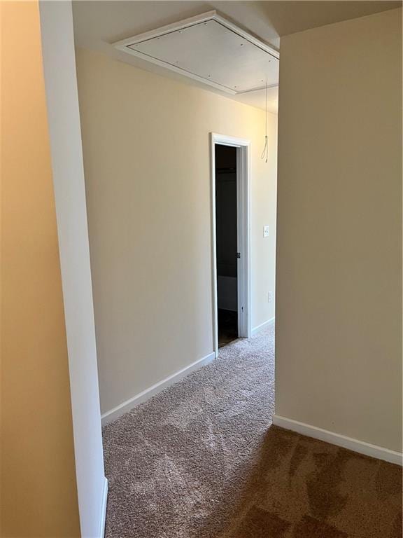 carpeted spare room featuring baseboards and attic access