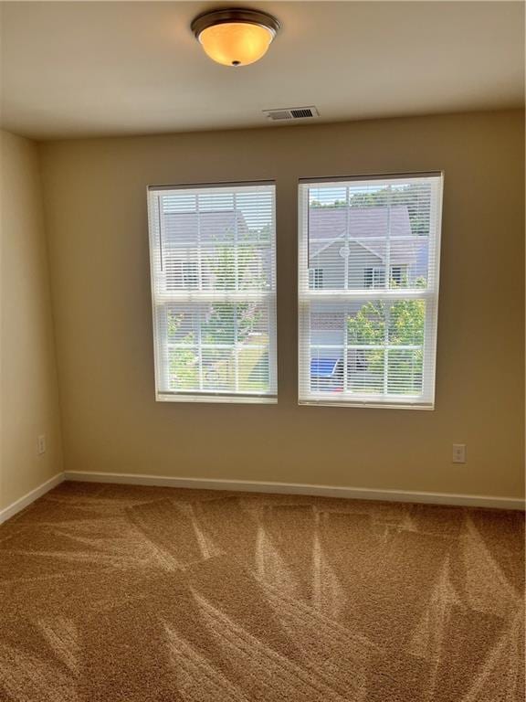 carpeted empty room featuring visible vents and baseboards