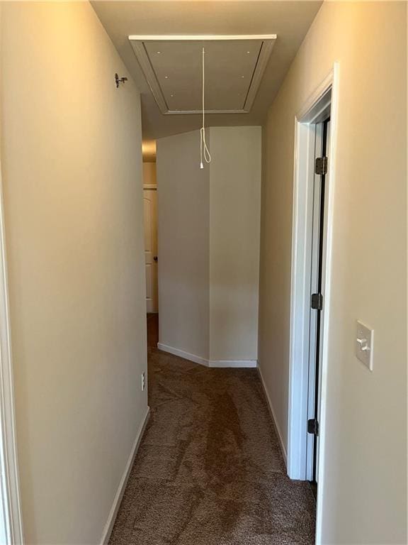 corridor with baseboards, attic access, and carpet flooring
