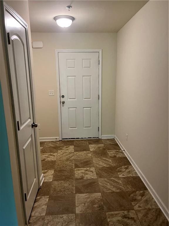 doorway featuring stone finish flooring and baseboards