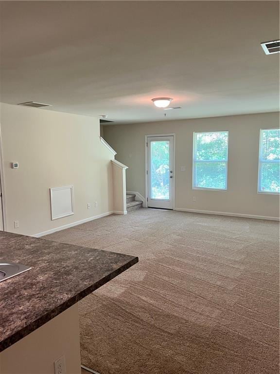 empty room with visible vents, stairway, light carpet, and baseboards
