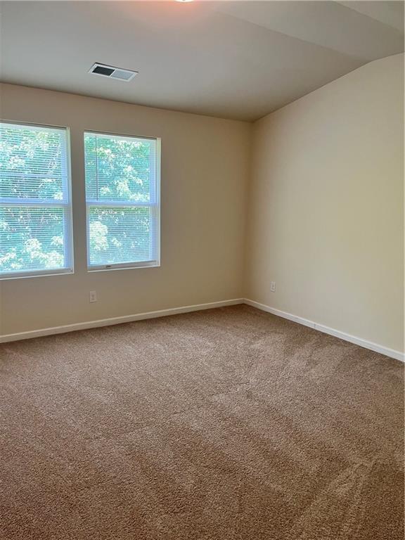 spare room featuring carpet, visible vents, and baseboards