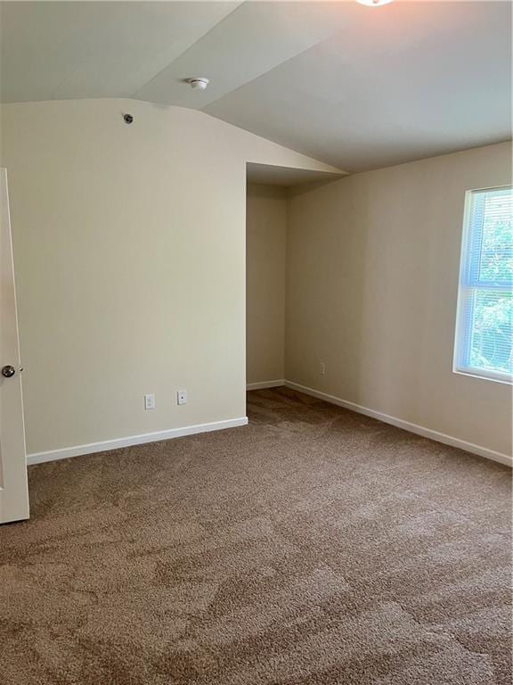 carpeted spare room with lofted ceiling and baseboards
