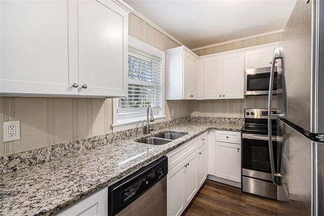 kitchen with dark wood-type flooring, ornamental molding, appliances with stainless steel finishes, white cabinets, and a sink