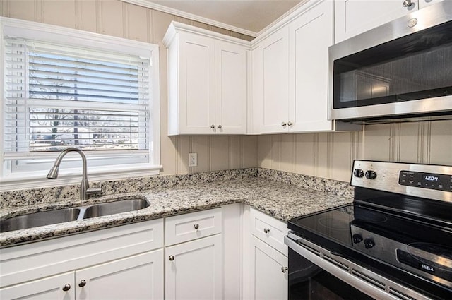 kitchen featuring a sink, white cabinets, light stone countertops, and stainless steel appliances