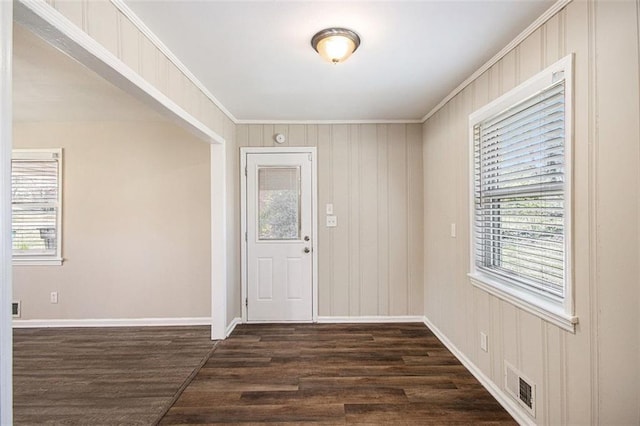 foyer entrance featuring dark wood finished floors, crown molding, baseboards, and visible vents