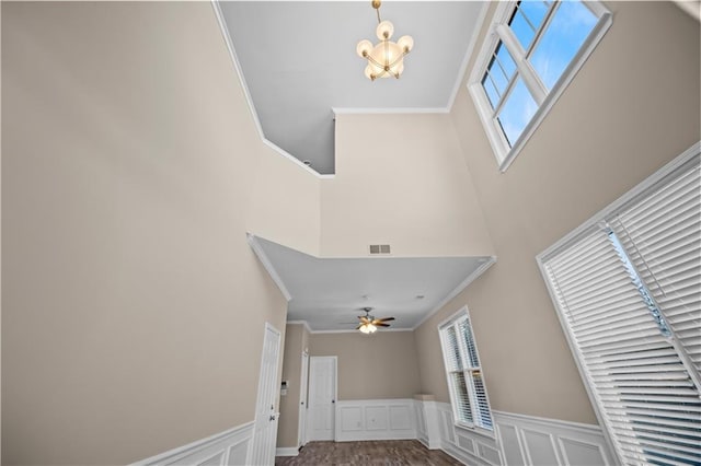 foyer entrance featuring a high ceiling, ornamental molding, and ceiling fan with notable chandelier