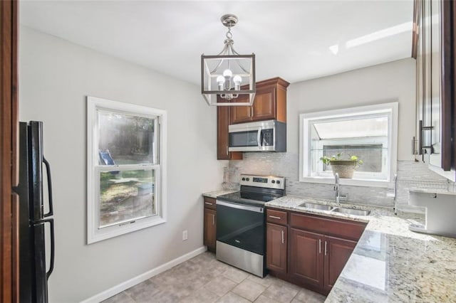 kitchen with light stone countertops, sink, stainless steel appliances, pendant lighting, and a chandelier