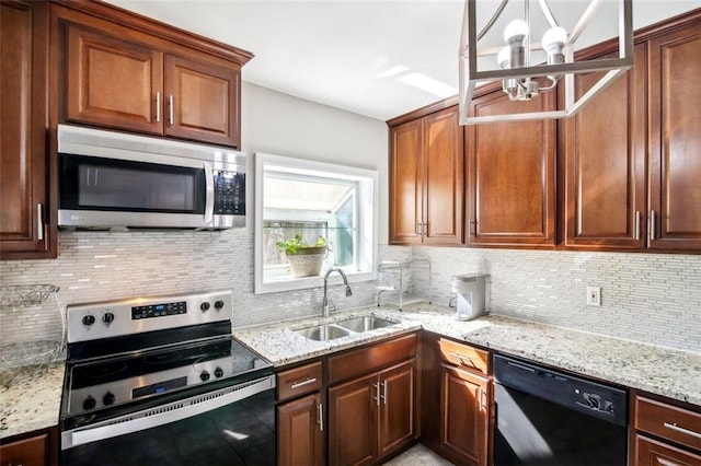 kitchen featuring stainless steel appliances, light stone countertops, sink, and an inviting chandelier