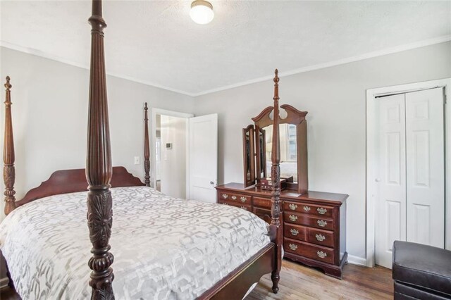 bedroom featuring a closet, crown molding, and wood-type flooring