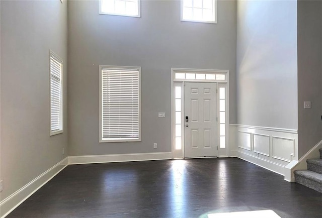 foyer with a wainscoted wall, a high ceiling, stairway, and dark wood finished floors