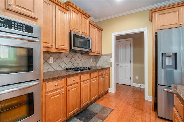 kitchen featuring tasteful backsplash, light wood-style flooring, dark stone countertops, stainless steel appliances, and crown molding