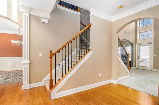 staircase with arched walkways, ornamental molding, wood finished floors, and visible vents