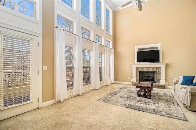 living room featuring a brick fireplace, carpet flooring, a ceiling fan, and baseboards