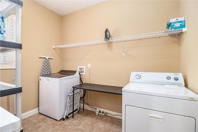 clothes washing area featuring laundry area, separate washer and dryer, light tile patterned flooring, and baseboards