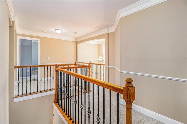 hallway featuring baseboards, crown molding, an upstairs landing, carpet flooring, and a notable chandelier