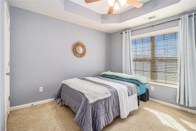 bedroom featuring carpet flooring, a raised ceiling, visible vents, and baseboards