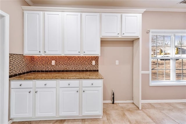 kitchen featuring white cabinetry, decorative backsplash, ornamental molding, and dark stone counters