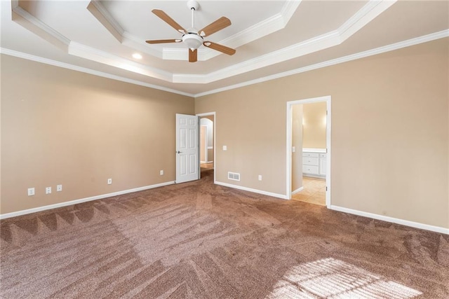 unfurnished bedroom with crown molding, ensuite bath, a tray ceiling, and carpet