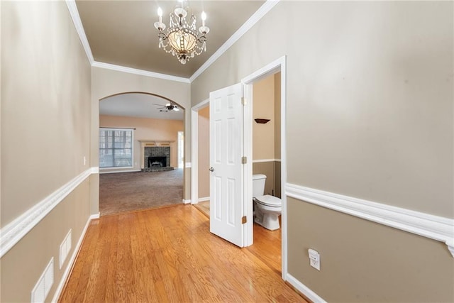 hallway with an inviting chandelier, light hardwood / wood-style flooring, and ornamental molding