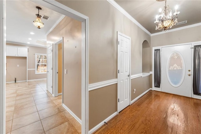 entrance foyer featuring crown molding, light tile patterned flooring, and a chandelier