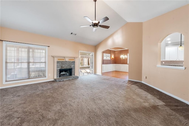 unfurnished living room featuring a brick fireplace, a wealth of natural light, ceiling fan, and carpet flooring