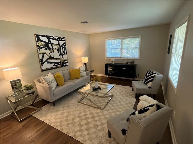 living room featuring wood finished floors, visible vents, and baseboards