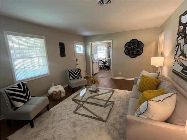 living room with baseboards, visible vents, and wood finished floors